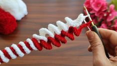 someone is crocheting red and white yarn on the end of a skewer