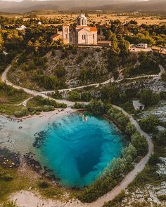 an aerial view of a church with blue water