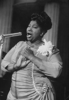 a black and white photo of a woman singing into a microphone