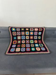 a crocheted rug on top of a gray couch