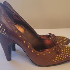 Description Miu Miu Leather Pumps* Brown Semi-Pointed Toes With Studded Accents Block Heels Authentic Pre-Loved Miu Miu Brown Leather Studded Pump. Stylish Brown Leather Pumps With Gold Style. Imported. Made In Italy. Features Gold Time Studs. Size 8 Does Not Include Boxdust Bag. Used, In Good Condition. Heels: 4" Details:Moderate Scuffs At Soles; Minor Scuffs At Heel Cap And Toe Box; Minor Blemish At Heel; Light Creasing At Exterior; Minor Residue At Insoles. Used, In Good Condition. Please Zoo Studded Leather Open Toe Heels, Studded Open Toe Leather Heels, Leather Open Toe Heels With Studs, Spring High Heels With Gold Studs, Studded Leather High Heels, Leather High Heels With Studs, Designer Leather Miu Miu Heels, Designer Leather Heels By Miu Miu, Designer Miu Miu Leather Heels