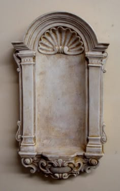 a white wall mounted fountain with an ornate design