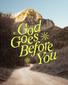 the words god goes before you are written in green on a dirt road near a mountain