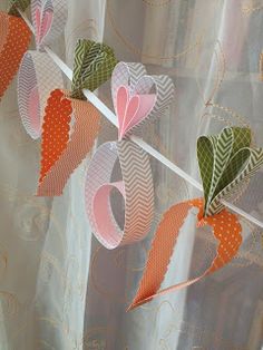 some paper hearts are hanging on a line next to the curtains in front of a window