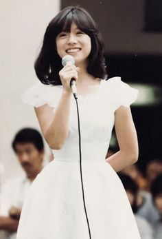 a woman in a white dress holding a microphone