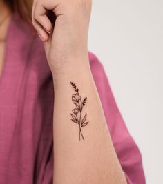 a woman's arm with a small flower tattoo on the left side of her arm