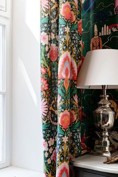 a lamp is next to a window with colorful curtains