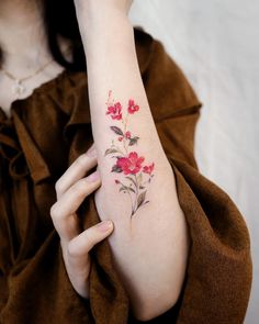 a woman's arm with red flowers on the left side of her arm and an arrow in the middle