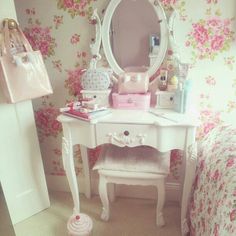 a white vanity with pink flowers on the wall behind it and a mirror above it