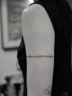 a woman's arm with barbed wire tattoo on the back of her left arm