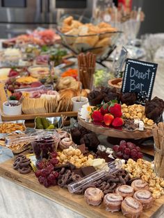 an assortment of snacks and desserts on a buffet table with a chalkboard sign