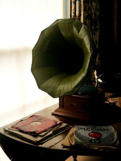 a green chair sitting on top of a wooden table next to a lamp and books