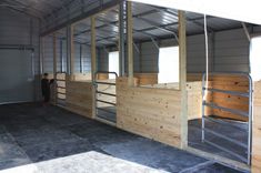 the inside of a horse barn with stalls