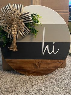 a wooden sign with the letter h on it and a bow hanging from it's side