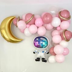 balloon garlands, balloons and an astronaut doll on a white table with pink and gold balloons