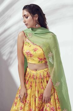 This printed cotton silk lehenga is pleated and flared at the waist.  It is paired with a matching bustier with a back opening with hooks.  This outfit is completed with a contrast dupatta with hand embroidery in zardosi and a scallop hemline. Yellow Skirt Outfits, Contrast Dupatta, Yellow Floral Skirt, Haldi Outfits, Crop Top Lehenga, Haldi Outfit, Printed Lehenga, Cotton Lehenga, Silk Crop Top