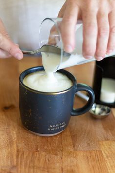 a person pouring milk into a mug