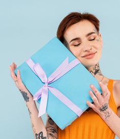 a woman with tattoos holding a blue gift box