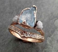 two gold rings with blue topazte and white diamonds on the bottom, set against a stone surface