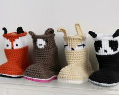 four crocheted booties are lined up on a shelf, each with an animal's face