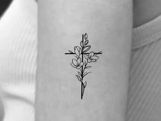 a cross and flowers tattoo on the left side of the arm, with black ink