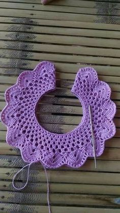 a purple crochet doily sitting on top of a wooden table next to a pair of scissors