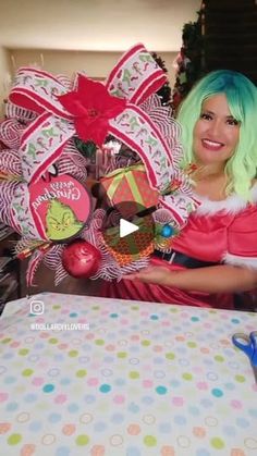 a woman with green hair holding up some christmas decorations