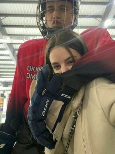 two people standing next to each other in front of a goalie helmet and net