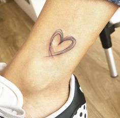 a small tattoo on the ankle of a woman's foot with a heart in it