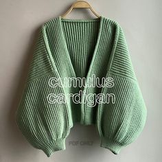 a green sweater hanging on a hanger with the words cumulus cardigan written below it