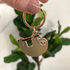 a hand holding a keychain with a sloth on it