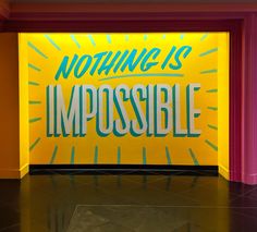 a sign that says nothing is impossible in front of a yellow and pink wall with rays