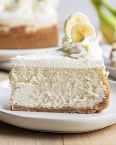 a piece of cake on a white plate with bananas and whipped cream topping in the middle