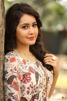 a beautiful young woman leaning against a tree