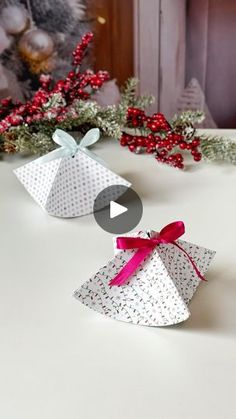 an origami box with a bow on it sitting on a table next to christmas decorations