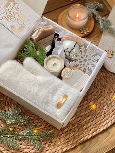 a white box filled with christmas items on top of a wicker table next to a candle