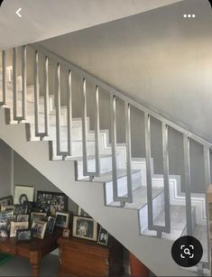 a stair case with pictures on the bottom, and framed photographs below it in an empty room