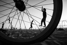 black and white photograph of people walking on the beach with their bikes tire spokes