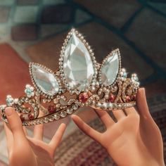 a close up of a person's hand holding a tiara