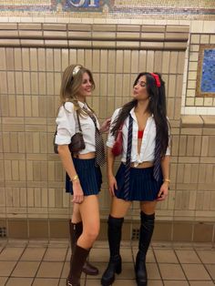 two young women standing next to each other in front of a wall with tiled walls