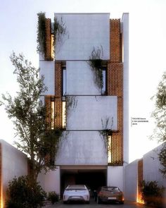 two cars parked in front of a tall building with plants growing on the side of it