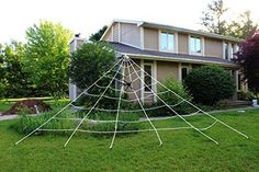 a spider web in front of a house with trees and bushes around it on the lawn