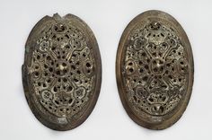 two metal plates with designs on them sitting side by side against a white background,