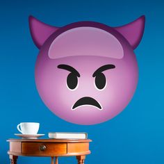 a table with a cup on it next to a wall sticker that looks like an angry cat