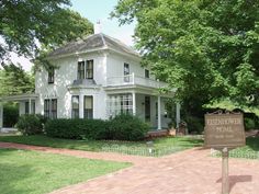 a large white house sitting on top of a lush green field