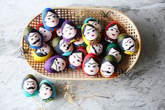 some eggs with faces painted on them are in a basket next to other eggs that look like people