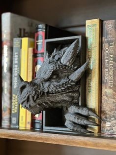 a book shelf filled with books and a statue of a dragon head on top of it