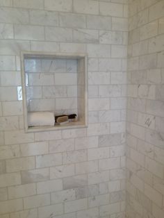 a bathroom with white marble walls and flooring, including a window in the wall