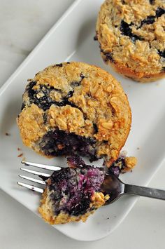 two blueberry muffins on a plate with a fork