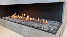 a modern fire place with rocks and stones on the bottom, as well as an open flame